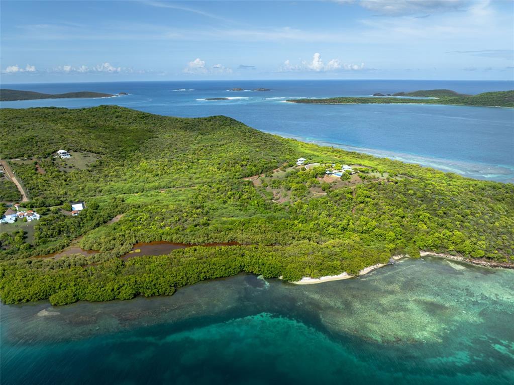 An aerial view shows a coastal landscape with lush green hills, a small pond, and ocean — 37 BARRIO FRAILES, CULEBRA, PR