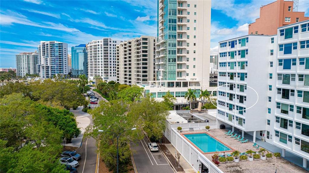 An aerial view of a white apartment building with a pool and surrounding city skyline — 33 S GULFSTREAM AVENUE UNIT 307, SARASOTA, FL