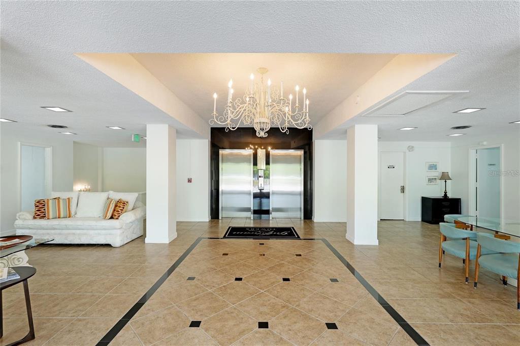 A lobby features a white chandelier, tiled floors, two elevators, and a seating area — 33 S GULFSTREAM AVENUE UNIT 307, SARASOTA, FL