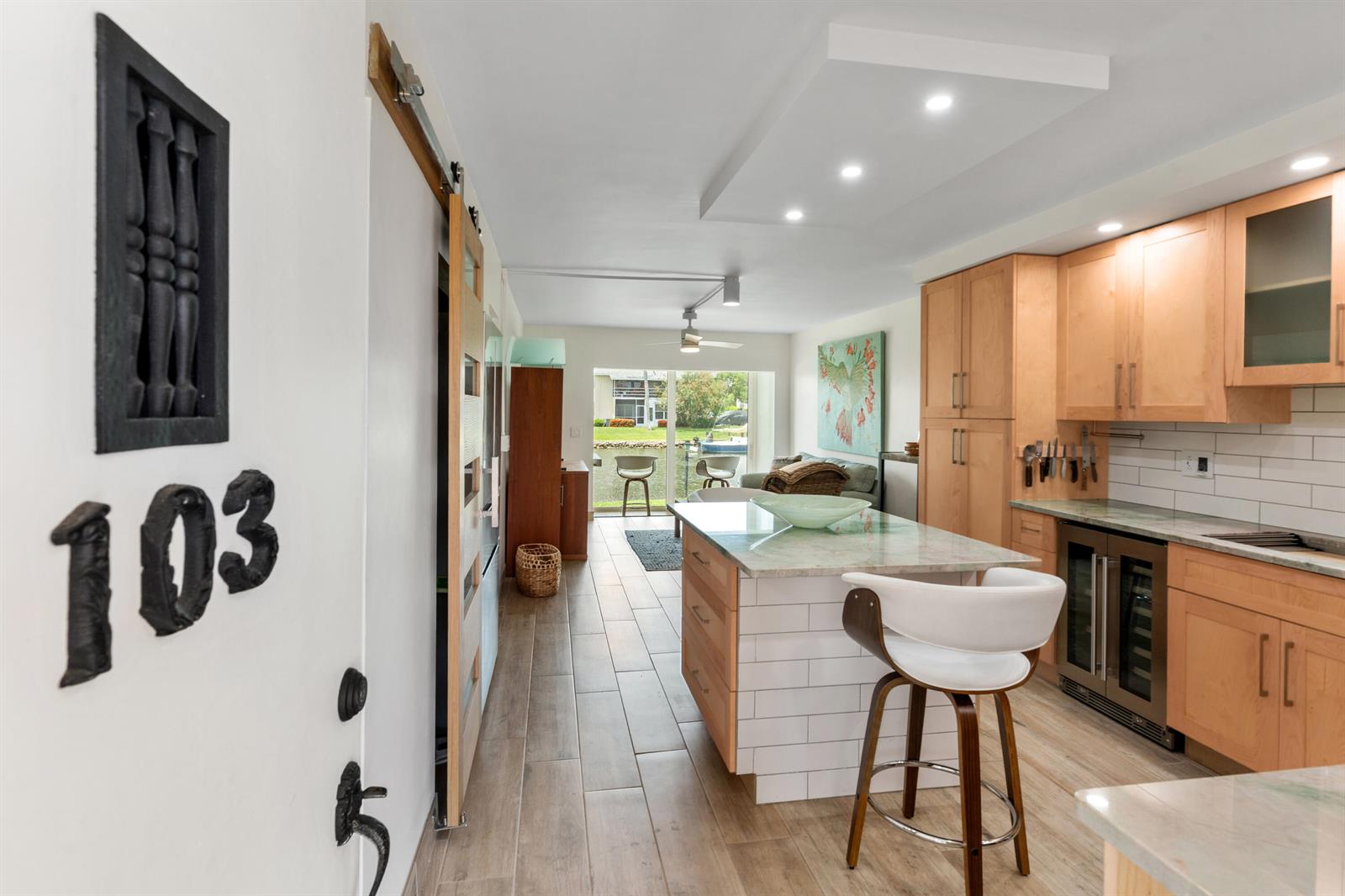 A kitchen with light wood cabinets, a marble-topped island, and a view of a canal — VERO BEACH, FL