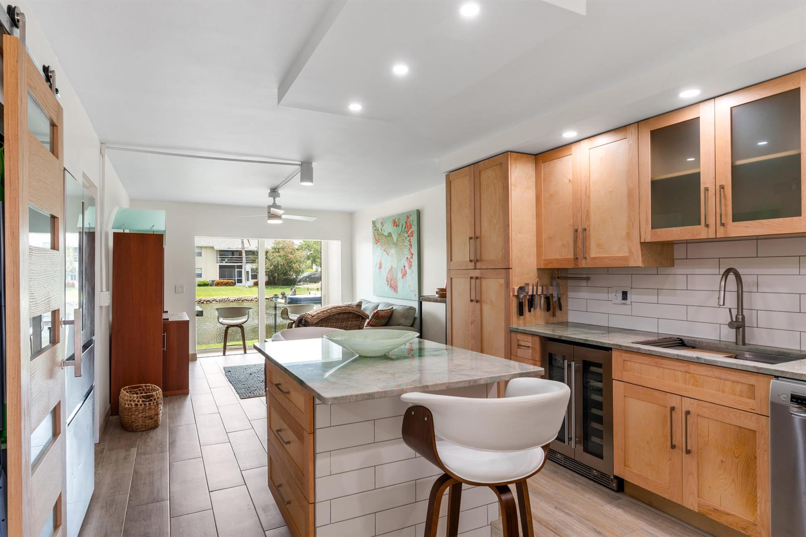A kitchen with light wood cabinets, a stone-topped island, and a view of a canal — VERO BEACH, FL
