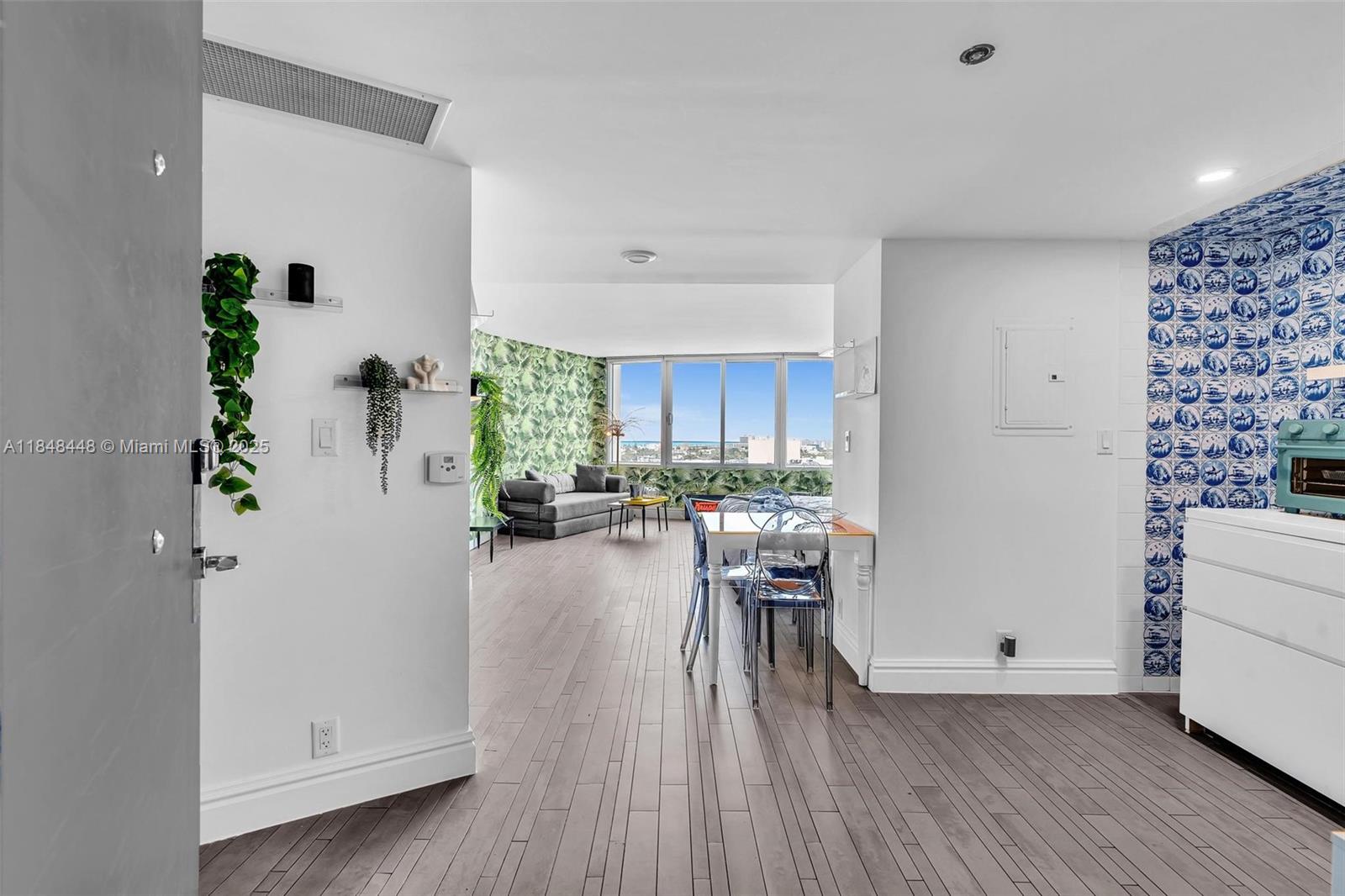 An interior view shows a living area with wood floors, palm-print wallpaper, and blue-tiled walls — 1100 West Ave # 1019, Miami Beach FL 33139, MIAMI BEACH, FL