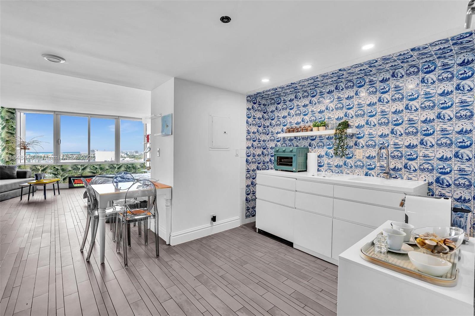 A kitchen and dining area features blue and white patterned tile walls and wood flooring — 1100 West Ave # 1019, Miami Beach FL 33139, MIAMI BEACH, FL