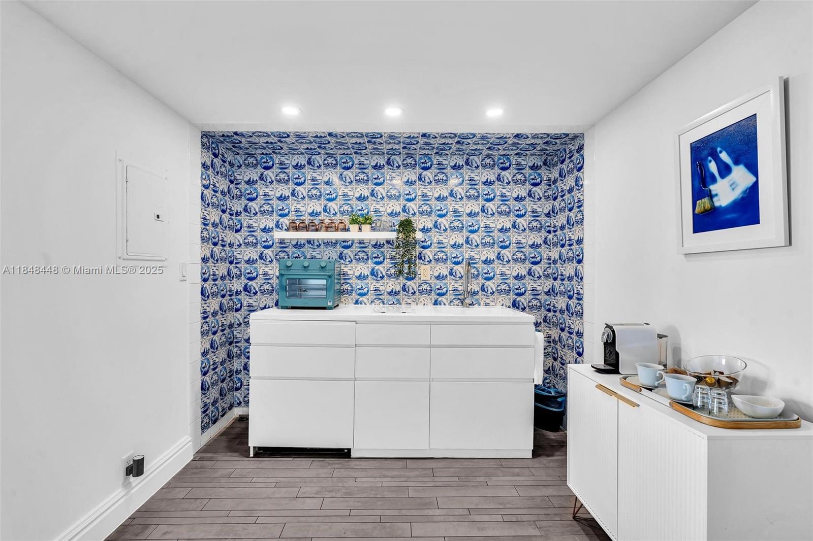 A kitchen area features blue and white patterned tile walls and white cabinetry — 1100 West Ave # 1019, Miami Beach FL 33139, MIAMI BEACH, FL
