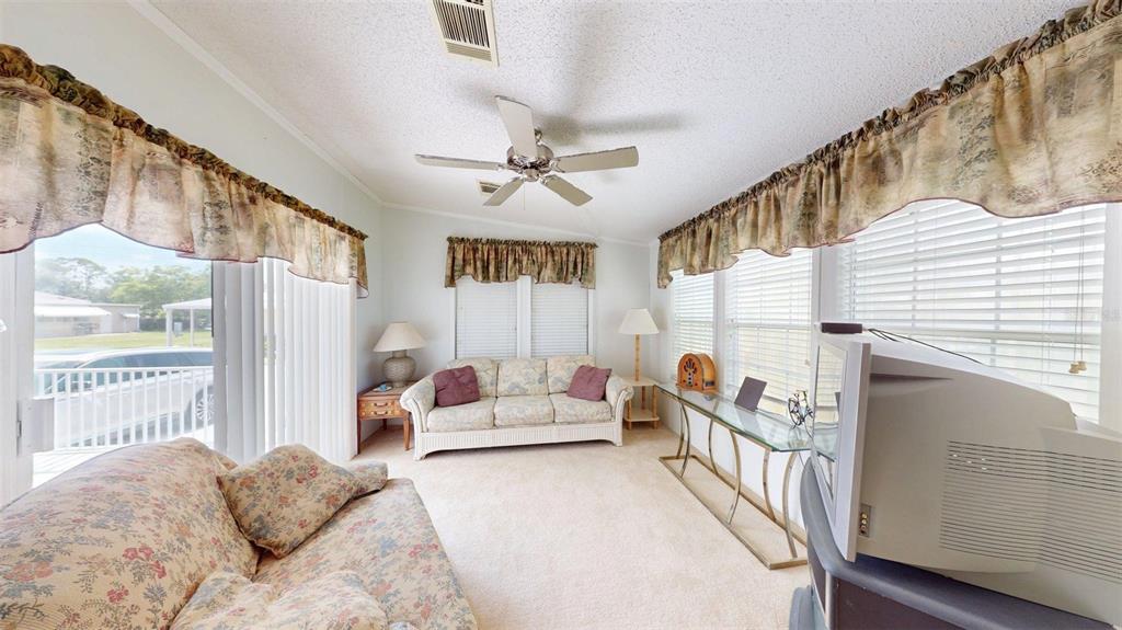 A sunroom features floral sofas, a glass console table, a ceiling fan, and window blinds — 2100 KINGS HIGHWAY UNIT 534, PUNTA GORDA, FL