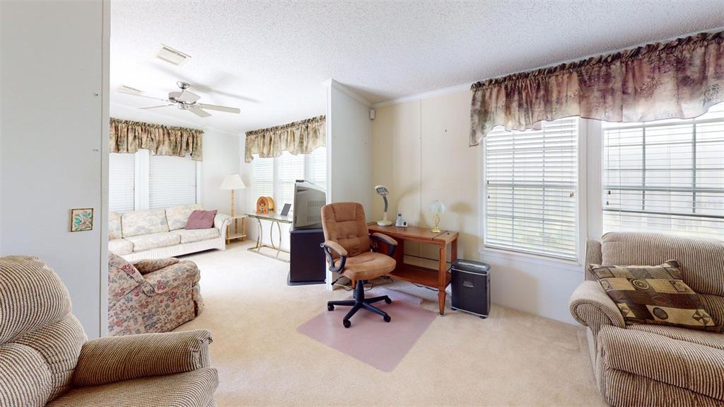 A living room features beige carpet, multiple seating areas, and a small wooden desk — 2100 KINGS HIGHWAY UNIT 534, PUNTA GORDA, FL