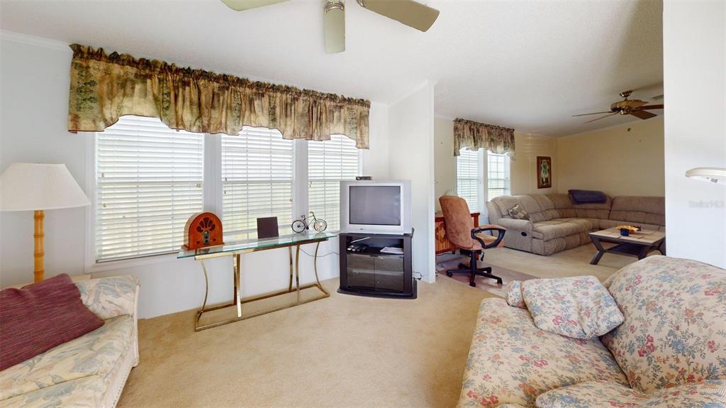 A living room features beige carpeting, floral furniture, a glass console table, and a television — 2100 KINGS HIGHWAY UNIT 534, PUNTA GORDA, FL