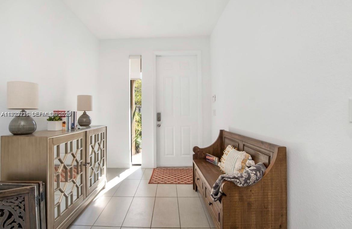An entryway features a wooden bench, a mirrored cabinet, and a door with a sidelight — 3327 NW 10th Ave, Pompano Beach FL 33064, POMPANO BEACH, FL