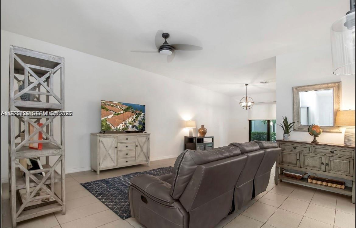A living room features a gray leather sofa, a television on a console, and shelving — 3327 NW 10th Ave, Pompano Beach FL 33064, POMPANO BEACH, FL