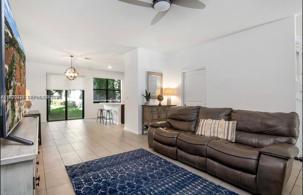 A living room with tile floors, a brown leather sofa, and an adjacent kitchen area — 3327 NW 10th Ave, Pompano Beach FL 33064, POMPANO BEACH, FL