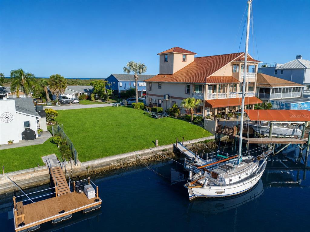 An aerial view shows a waterfront house with a large lawn and a sailboat docked — SOUTHWIND DRIVE lot 130, HUDSON, FL