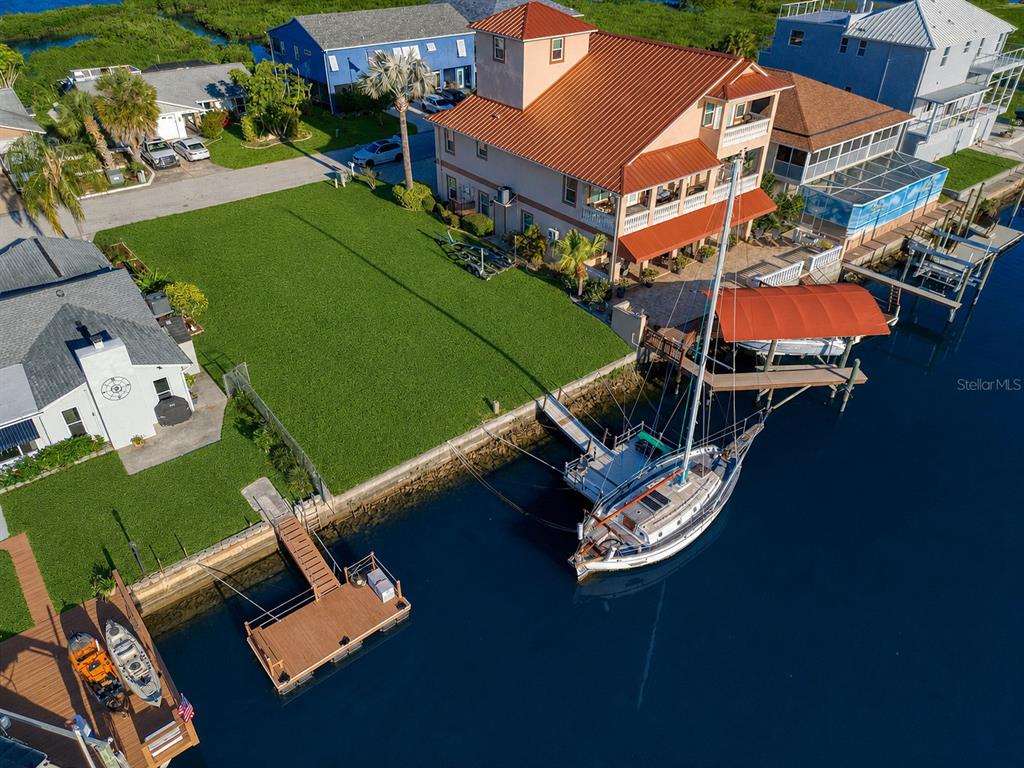 An aerial view shows a waterfront house with a large lawn, boat dock, and sailboat — SOUTHWIND DRIVE lot 130, HUDSON, FL