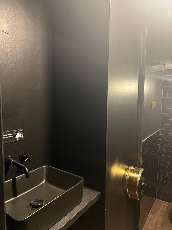 A modern bathroom features a matte black vessel sink, dark walls, and a gold dispenser — 924 71st Street, Miami Beach FL 33141, MIAMI BEACH, FL