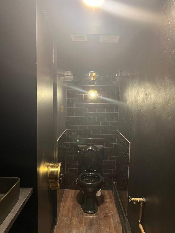 A small bathroom features black subway tile walls, a black toilet, and brass fixtures — 924 71st Street, Miami Beach FL 33141, MIAMI BEACH, FL