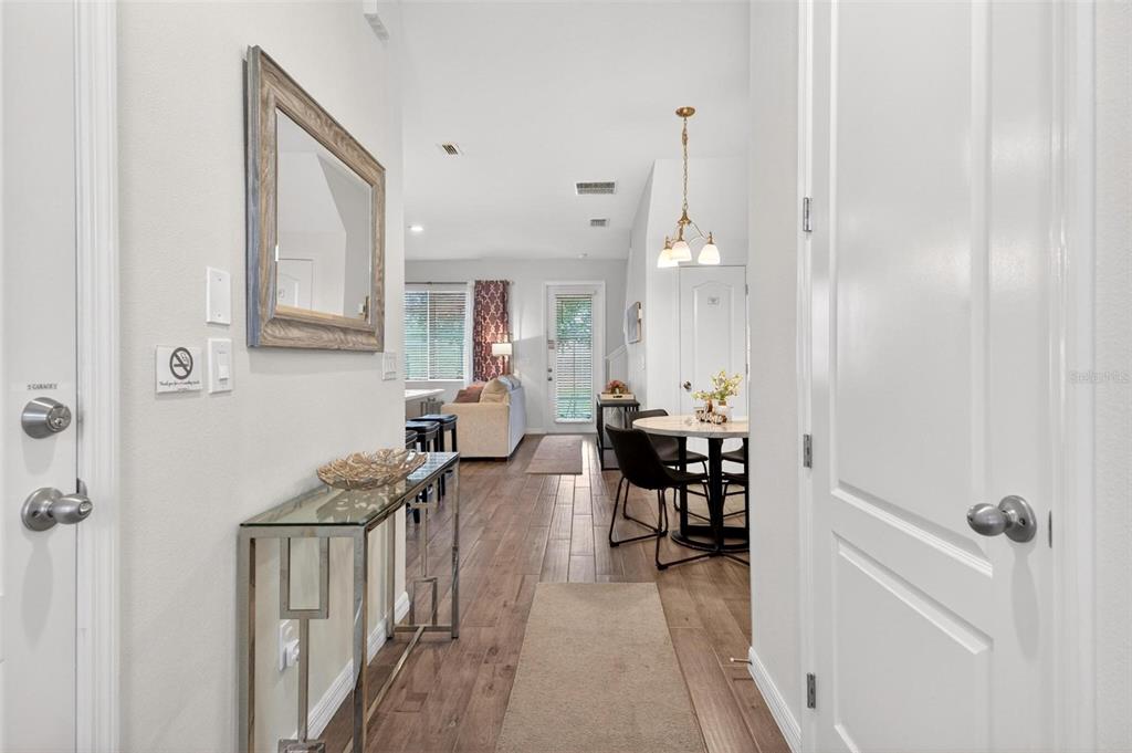 A bright entryway leads into an open-concept living and dining area with wood-look flooring — 701 BENOI DRIVE, DAVENPORT, FL