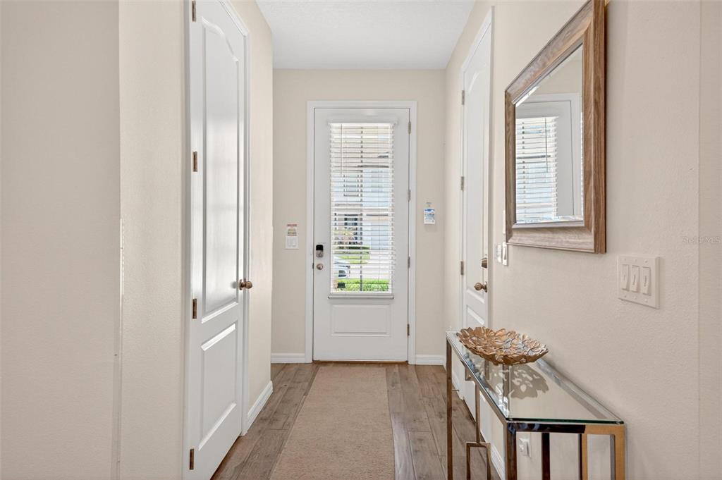 A bright entryway features wood-look flooring, a glass-topped console table, and a mirror — 701 BENOI DRIVE, DAVENPORT, FL