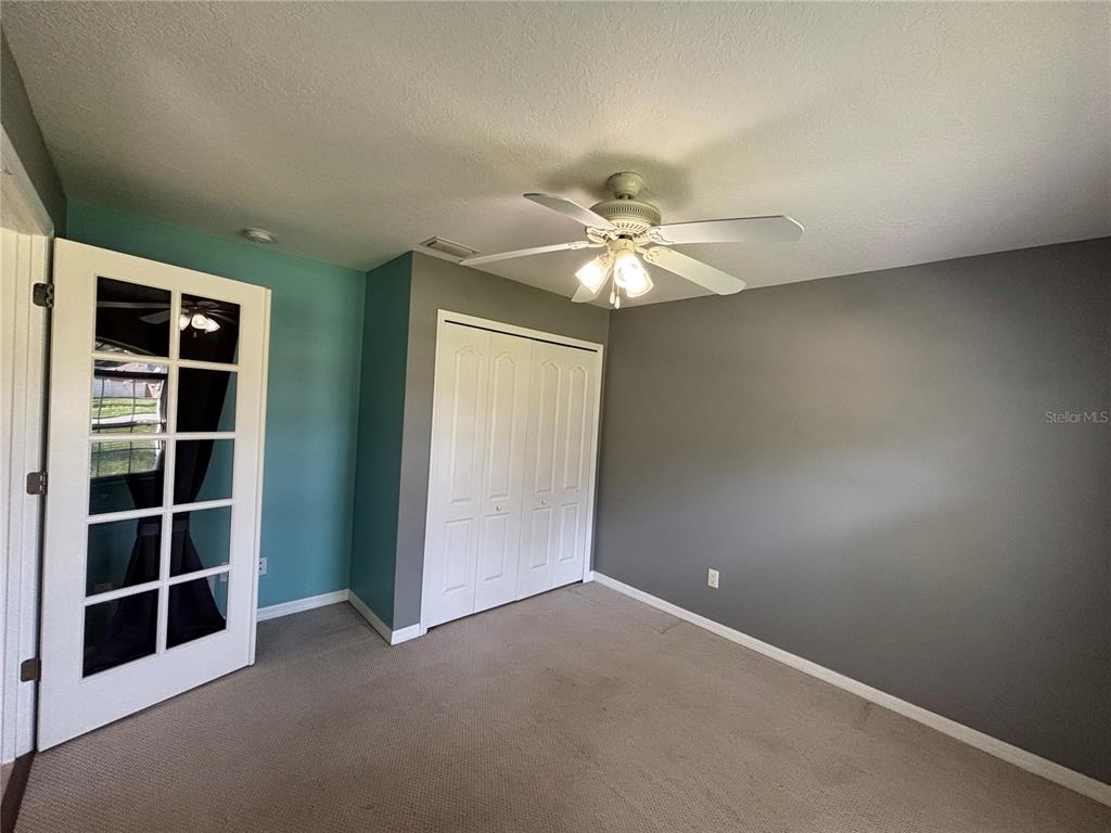 A bedroom features gray and teal walls, a ceiling fan, carpeted flooring, and a closet — 37 WHIPPOORWILL DRIVE, PALM COAST, FL