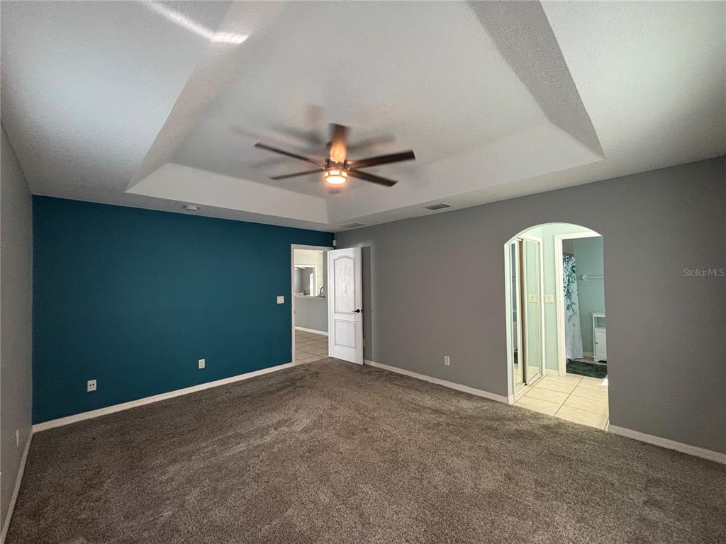 A bedroom features a tray ceiling, a teal accent wall, gray walls, and carpeted flooring — 37 WHIPPOORWILL DRIVE, PALM COAST, FL