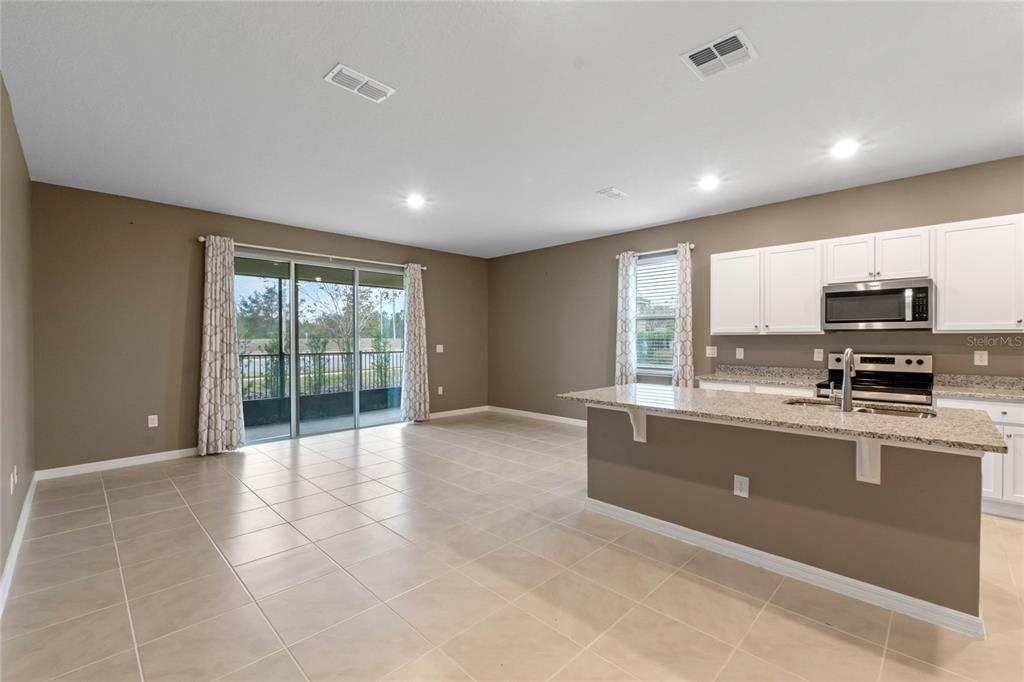 An open-concept kitchen with granite countertops and a living area with sliding glass doors — 961 LIDO DRIVE, HOWEY IN THE HILLS, FL