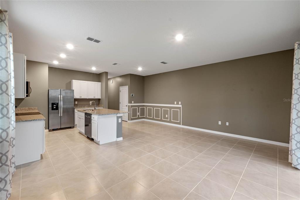 A kitchen with white cabinets, stainless steel appliances, and an island opens to a living area — 961 LIDO DRIVE, HOWEY IN THE HILLS, FL