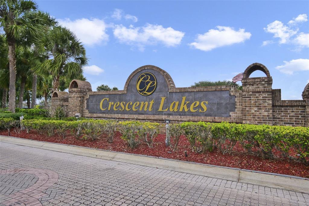 A brick monument sign for the Crescent Lakes community stands behind a landscaped garden bed — 2574 SAGE DRIVE, KISSIMMEE, FL