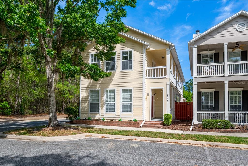 A two-story yellow house with a covered entryway and a second-story balcony — 11688 NW 17TH PLACE, GAINESVILLE, FL