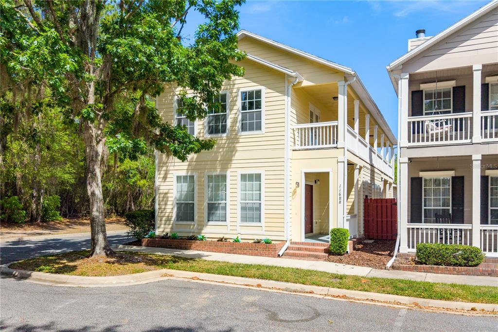 A two-story yellow house with a front porch and balcony sits next to a neighbor — 11688 NW 17TH PLACE, GAINESVILLE, FL