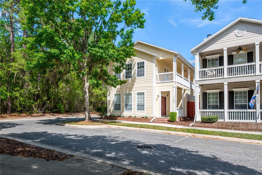 A two-story yellow house with a front porch stands next to a similar structure — 11688 NW 17TH PLACE, GAINESVILLE, FL