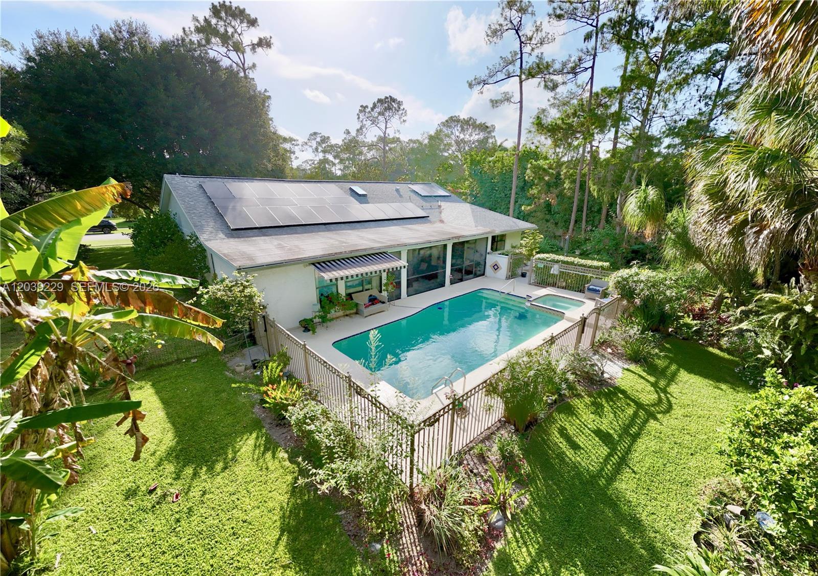 An aerial view shows a house with solar panels, a swimming pool, and a fenced yard — 172 Wild Pine Rd, Wellington FL 33414, WELLINGTON, FL