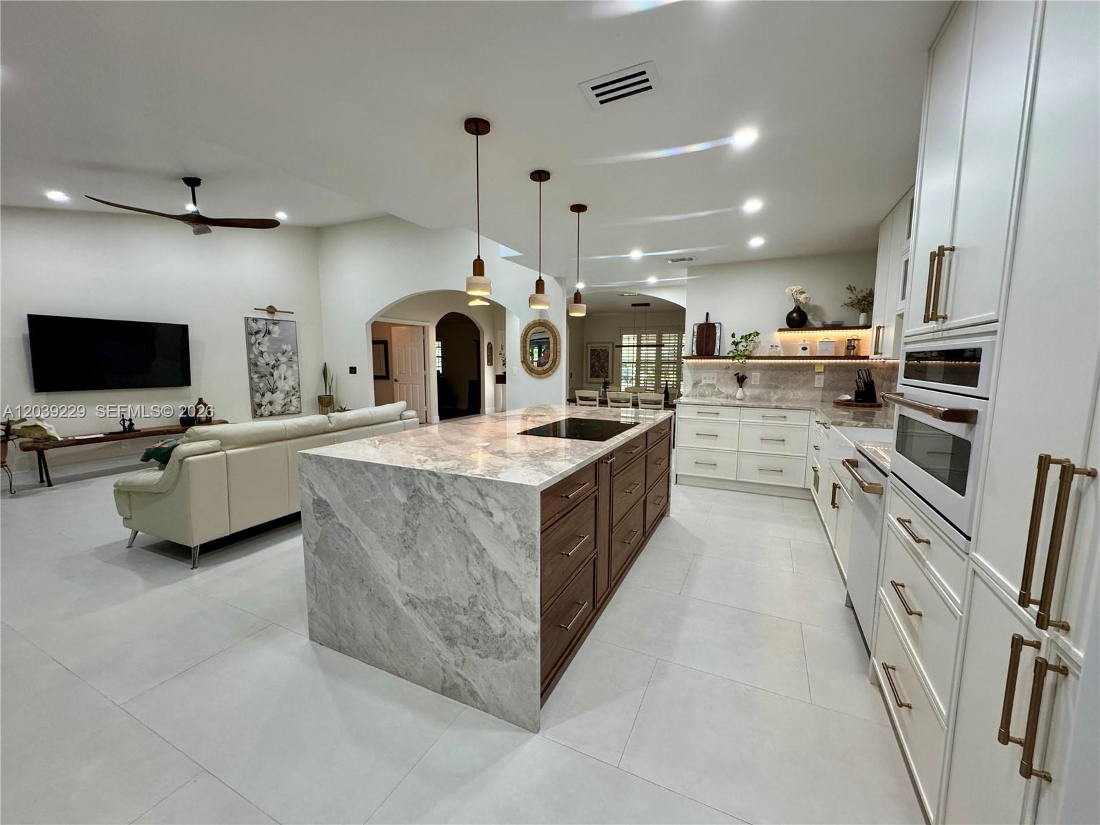 A modern kitchen features a large marble-topped island, dark wood cabinetry, and white appliances — 172 Wild Pine Rd, Wellington FL 33414, WELLINGTON, FL