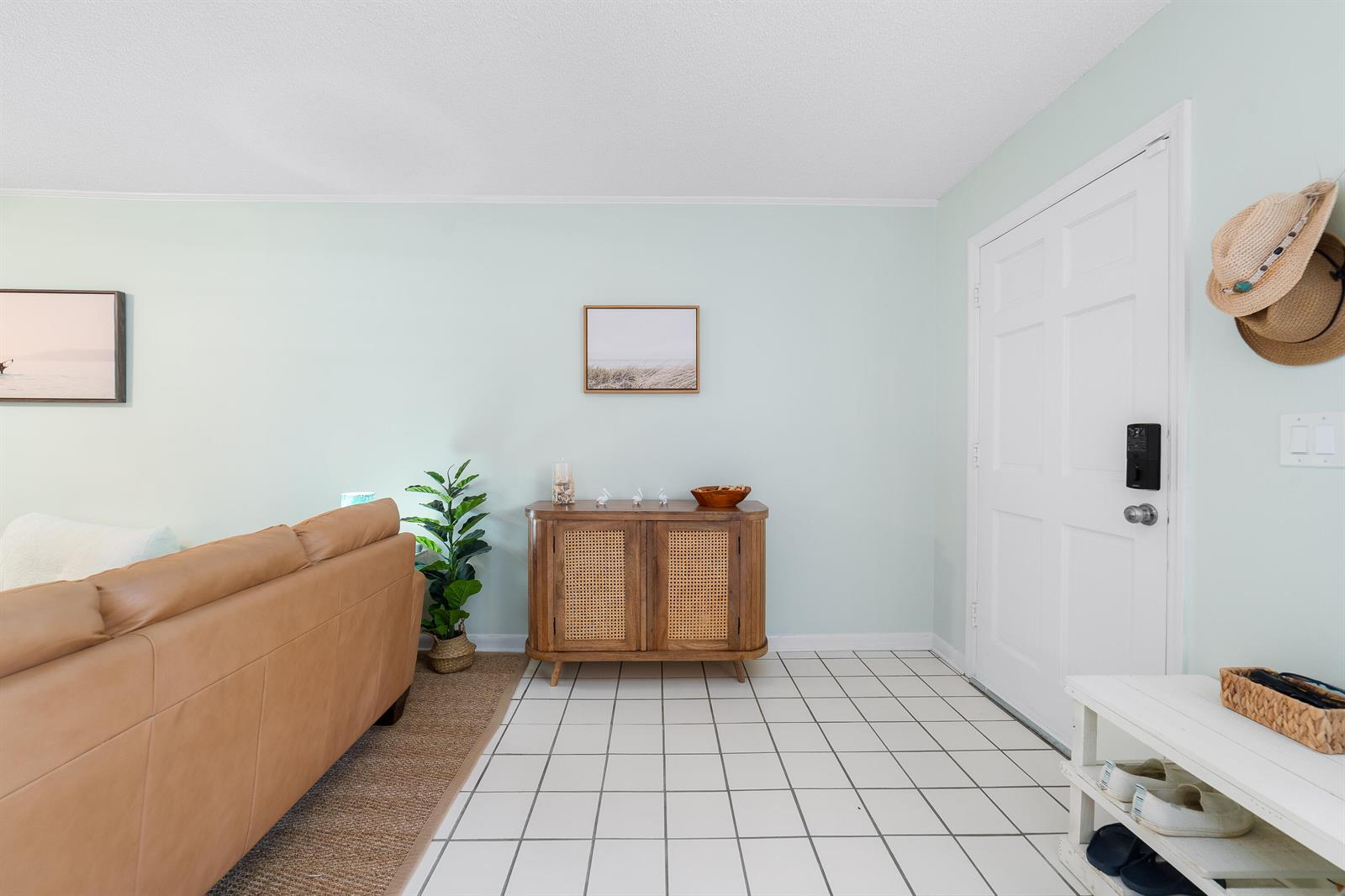 A light-walled entryway features a cane-front cabinet, a tan sofa, and white tiled flooring — 839 Camelia Lane # 8, Vero Beach FL 32963, VERO BEACH, FL