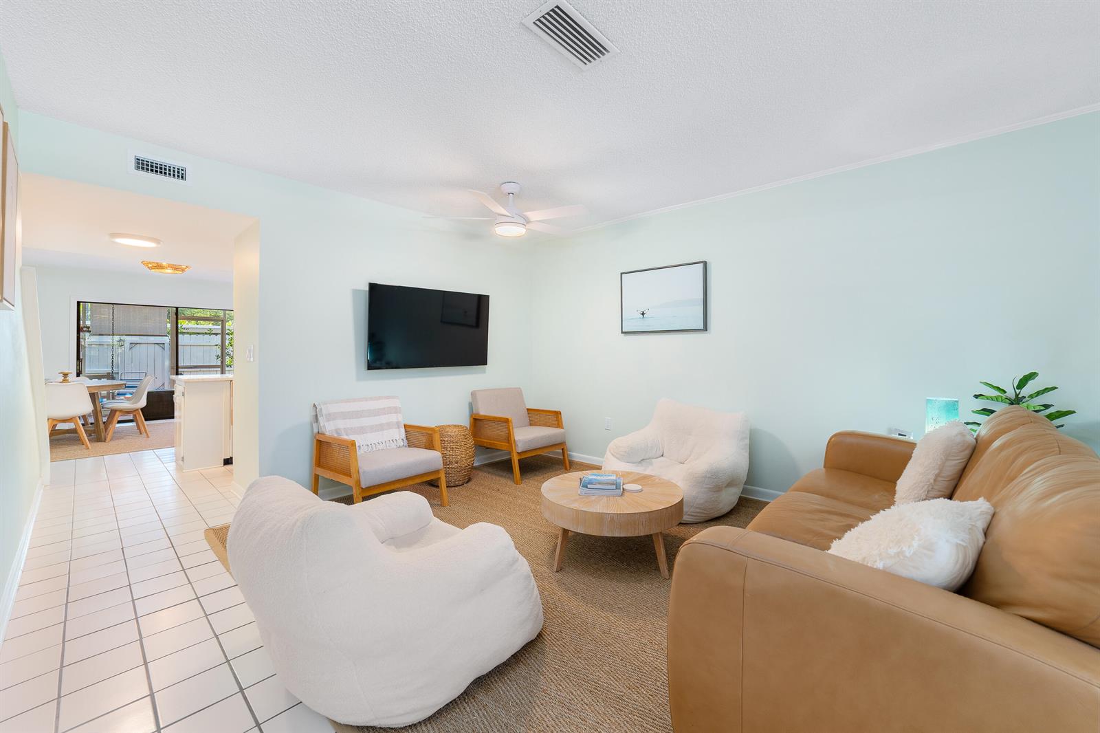 A living room features a tan leather sofa, white armchairs, a coffee table, and a television — 839 Camelia Lane # 8, Vero Beach FL 32963, VERO BEACH, FL