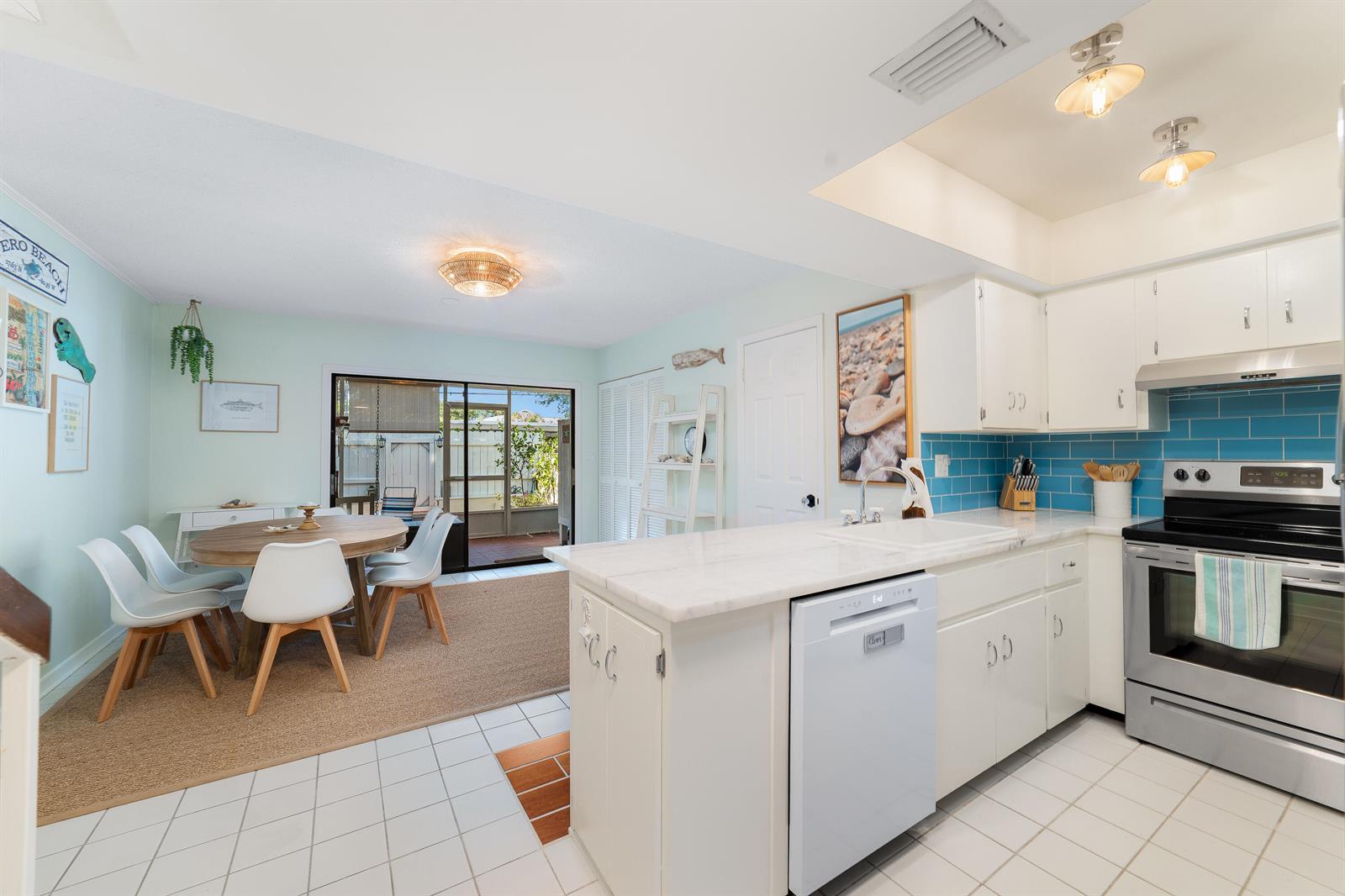 A kitchen with white cabinets and a dining area featuring a round wooden table — 839 Camelia Lane # 8, Vero Beach FL 32963, VERO BEACH, FL
