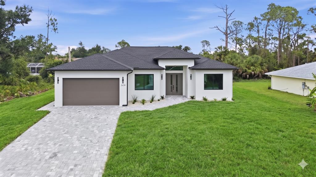 A modern single-story house with a white stucco exterior, dark roof, and paved driveway — 3638 LUBEC AVENUE, NORTH PORT, FL