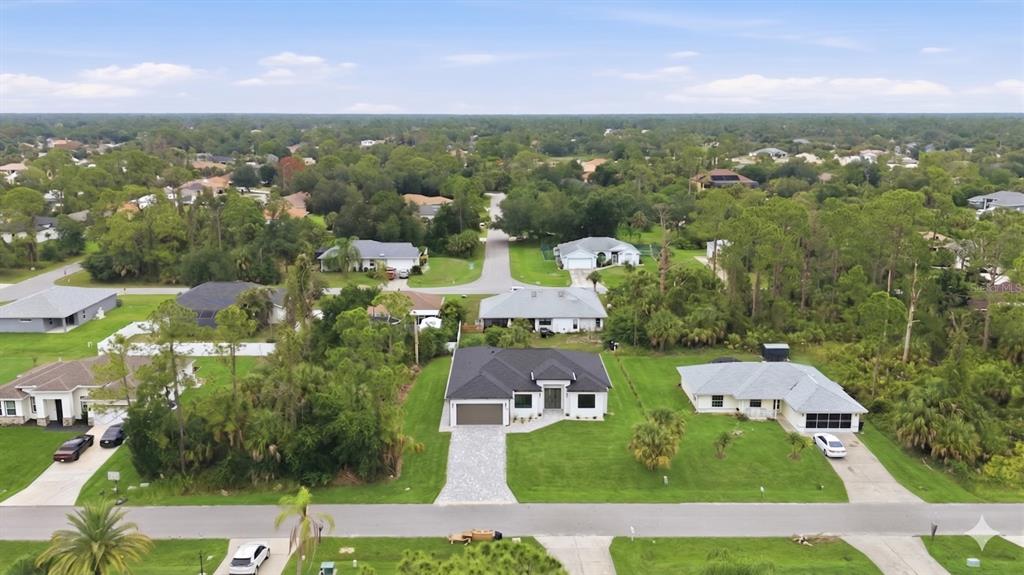 An aerial view shows a modern house with a dark roof surrounded by suburban greenery — 3638 LUBEC AVENUE, NORTH PORT, FL
