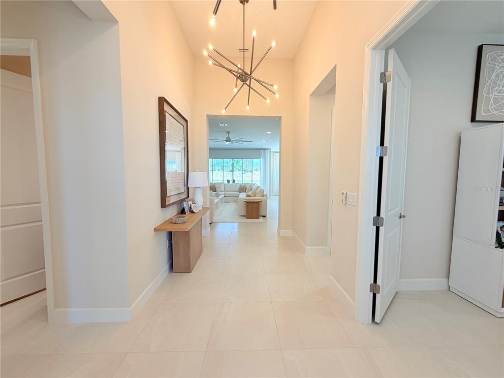 A bright foyer features light tile flooring, a modern sputnik chandelier, and a console table — 32700 NEROLI STREET, WESLEY CHAPEL, FL