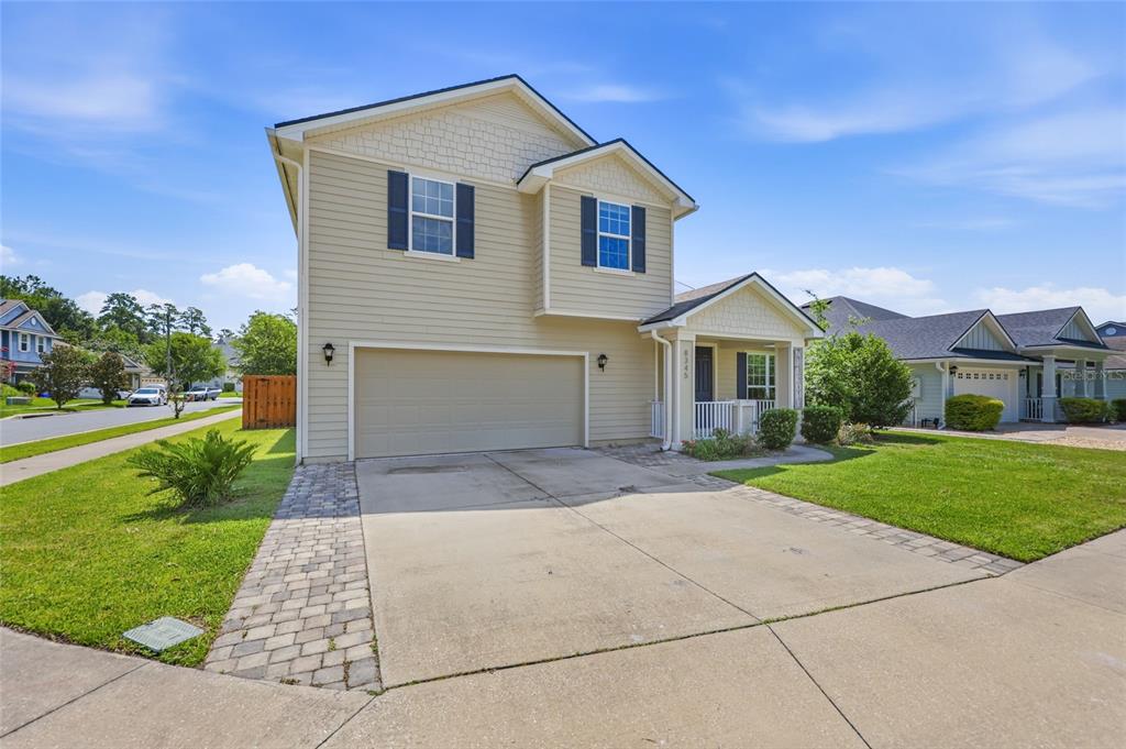 A two-story house with beige siding, a two-car garage, and a paved driveway — 8345 NW 54TH TERRACE, GAINESVILLE, FL