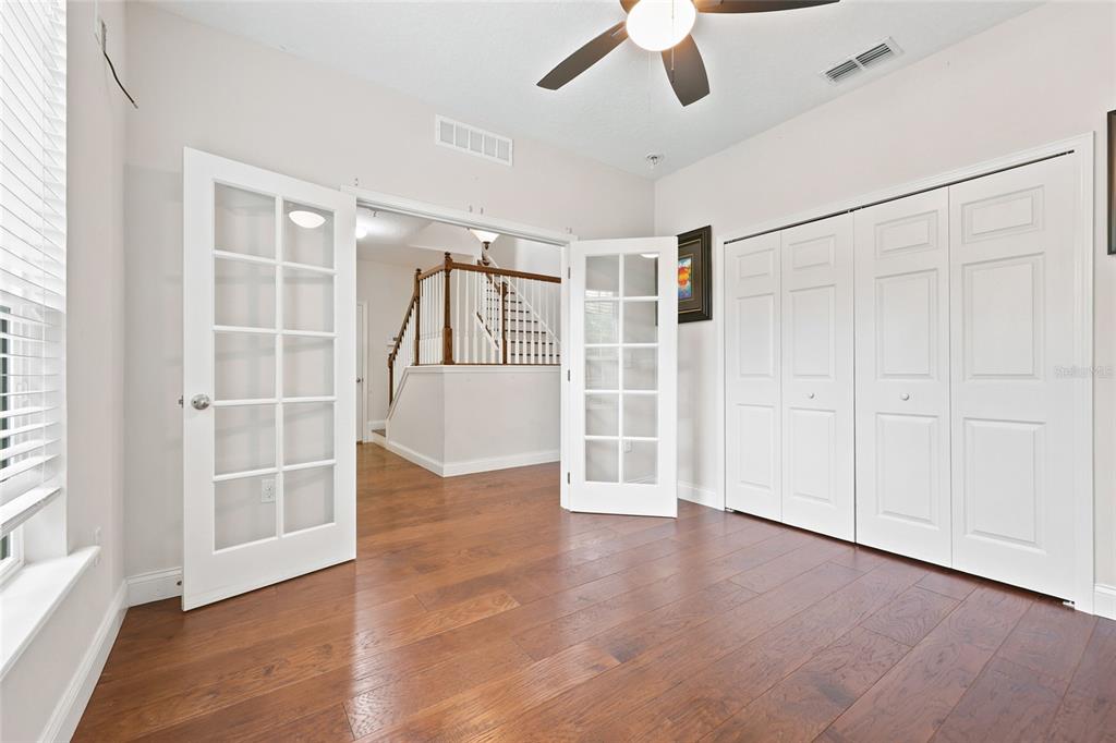 A room with hardwood floors, French doors, and a closet, looking toward a staircase — 8345 NW 54TH TERRACE, GAINESVILLE, FL