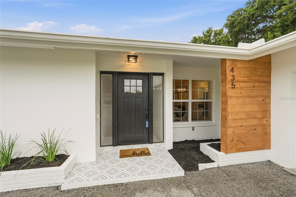 The exterior of a house features a black front door, wood-paneled accent wall, and entryway — 435 MEHLENBACHER ROAD, LARGO, FL