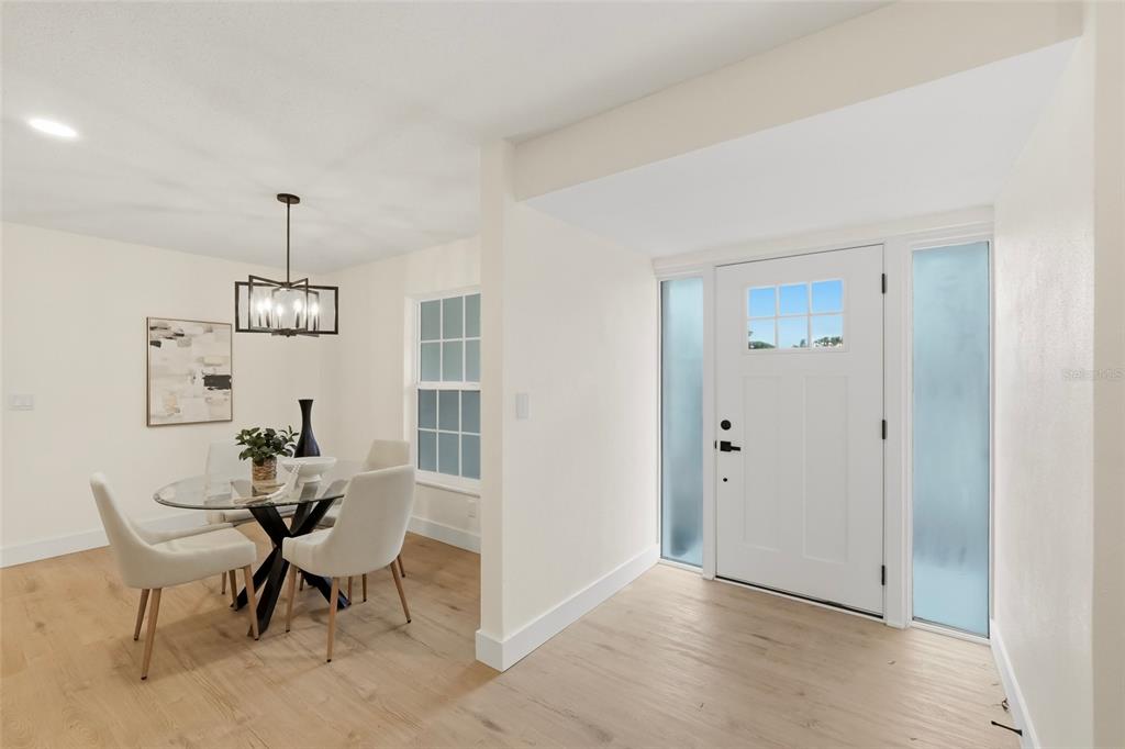 A dining area with a glass table and chairs sits next to a white entryway — 435 MEHLENBACHER ROAD, LARGO, FL