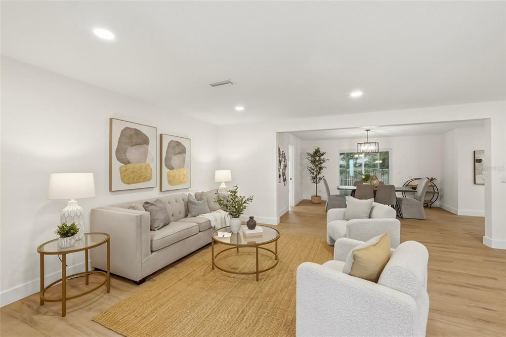 A living room with a beige sofa, two white armchairs, and light wood flooring — 435 MEHLENBACHER ROAD, LARGO, FL