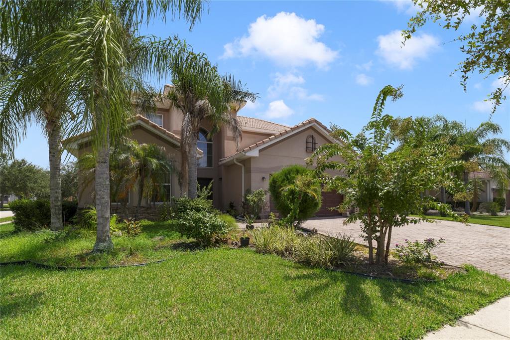 A two-story stucco house with a tiled roof, palm trees, and a paved driveway — 2300 EAGLE TALON COURT, KISSIMMEE, FL
