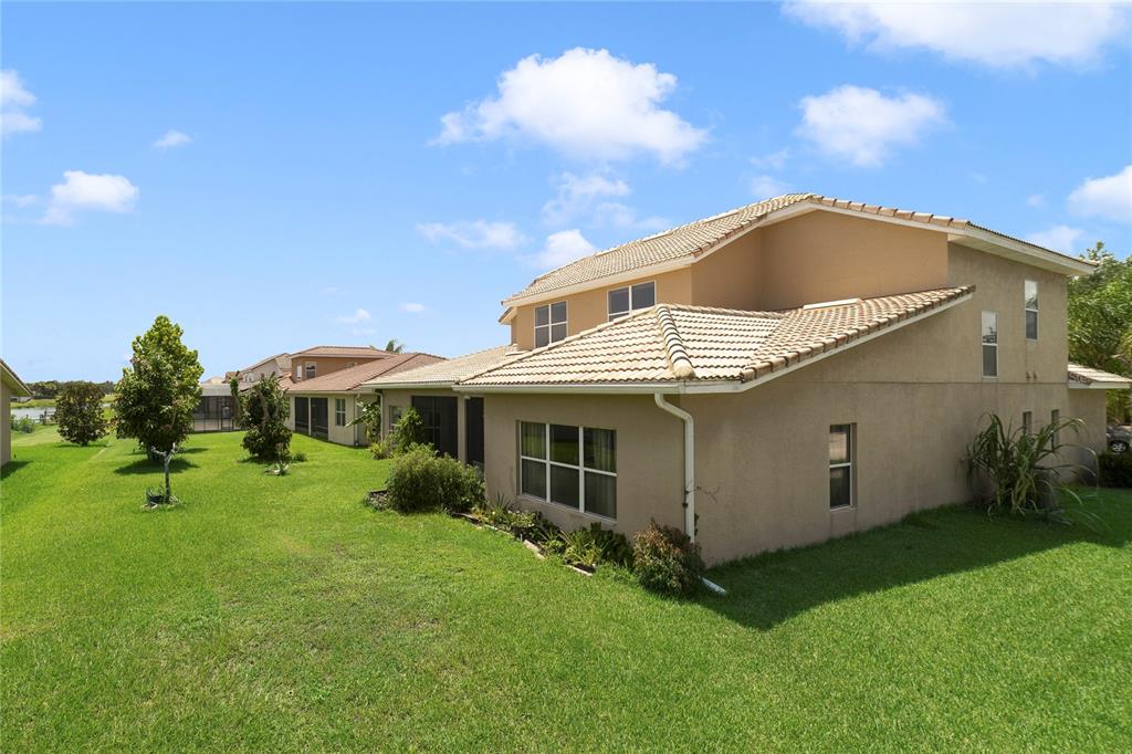 The exterior of a two-story tan stucco house with a tiled roof and grassy yard — 2300 EAGLE TALON COURT, KISSIMMEE, FL