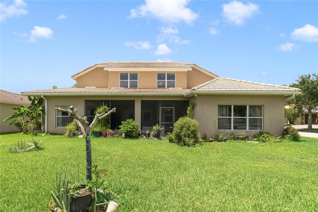 The exterior of a two-story house features a screened-in patio and a grassy backyard — 2300 EAGLE TALON COURT, KISSIMMEE, FL
