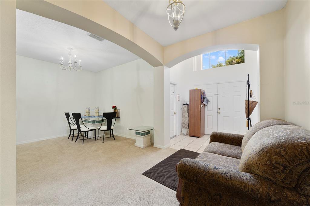A living room with beige carpet, a patterned sofa, and an adjacent dining area — 2300 EAGLE TALON COURT, KISSIMMEE, FL