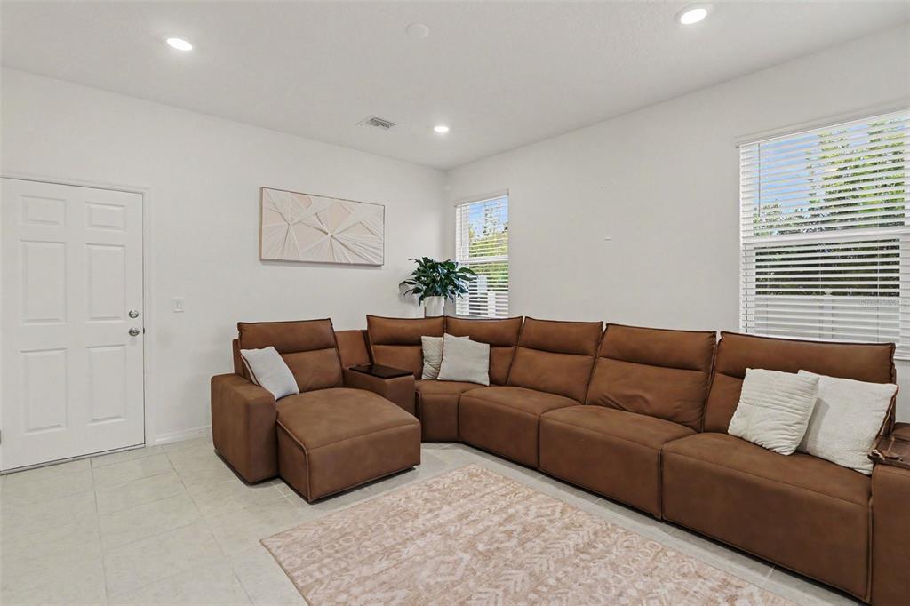 A dining area features a wooden table, four chairs, a toy kitchen, and sliding glass doors — 1180 WYCLIFFE WAY, ST CLOUD, FL