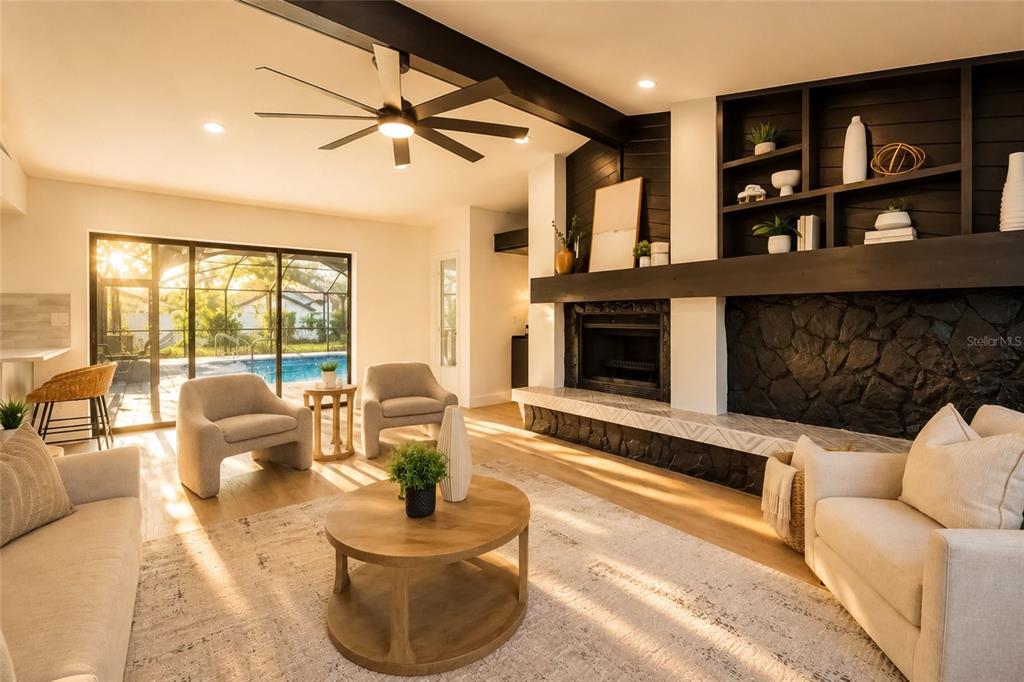 A living room features a stone fireplace, built-in shelving, and sliding doors opening to a pool — 2700 SEDGEFIELD COURT E, CLEARWATER, FL