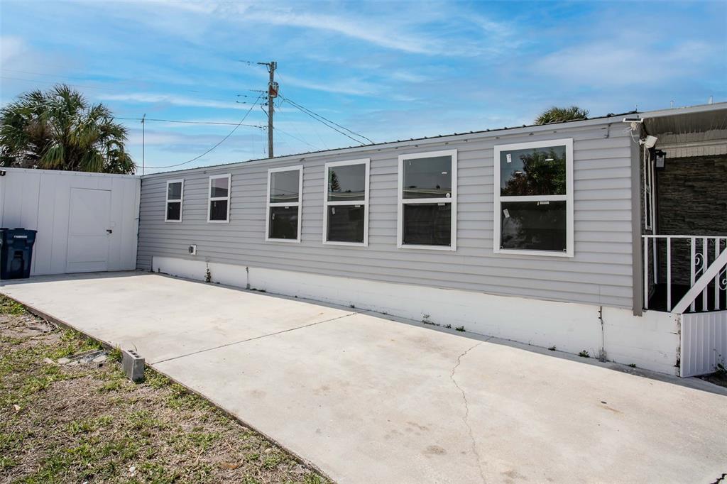 A side view of a mobile home with gray siding and a concrete driveway — 410 W 51ST AVENUE DRIVE W, BRADENTON, FL