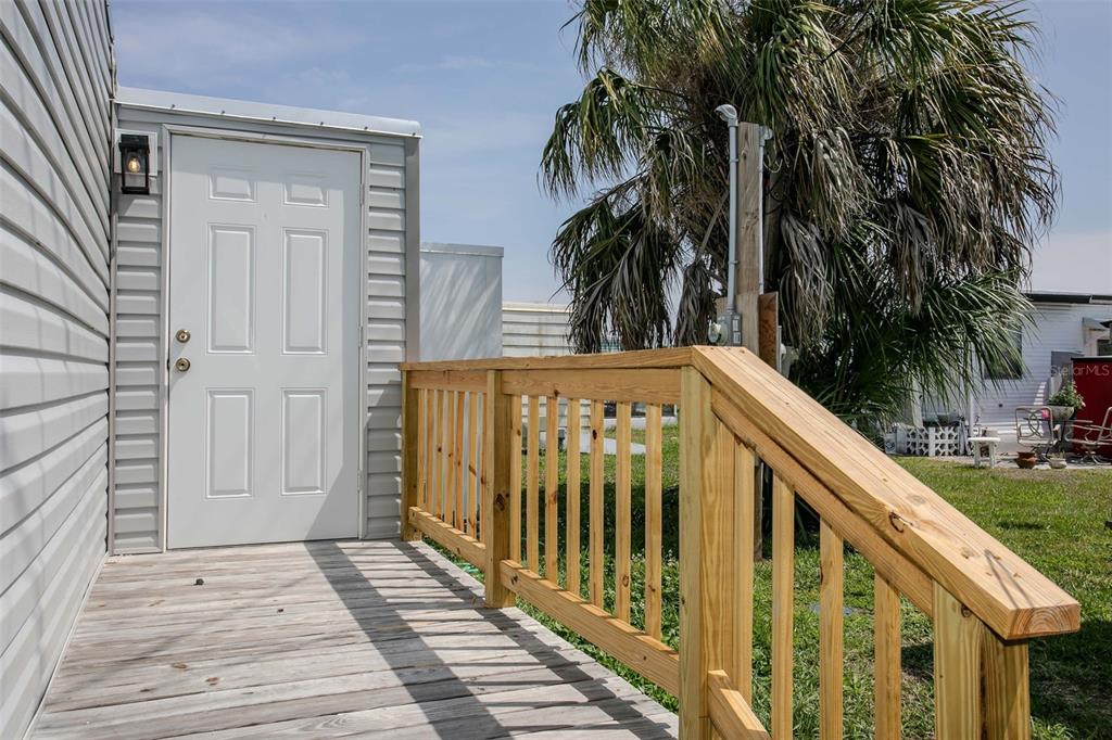 A wooden deck with a railing leads to a white door on the side of a building — 410 W 51ST AVENUE DRIVE W, BRADENTON, FL
