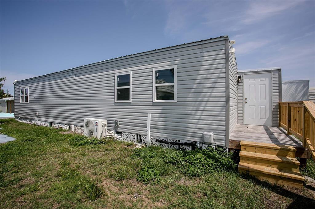 The exterior of a light gray mobile home features a wooden deck and stairs — 410 W 51ST AVENUE DRIVE W, BRADENTON, FL